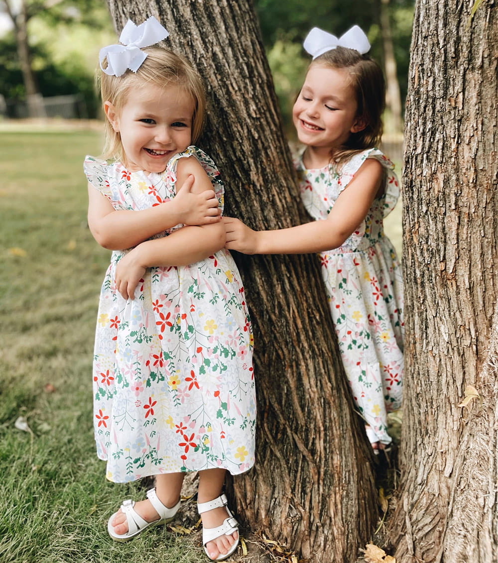 Two girls standing near a tree